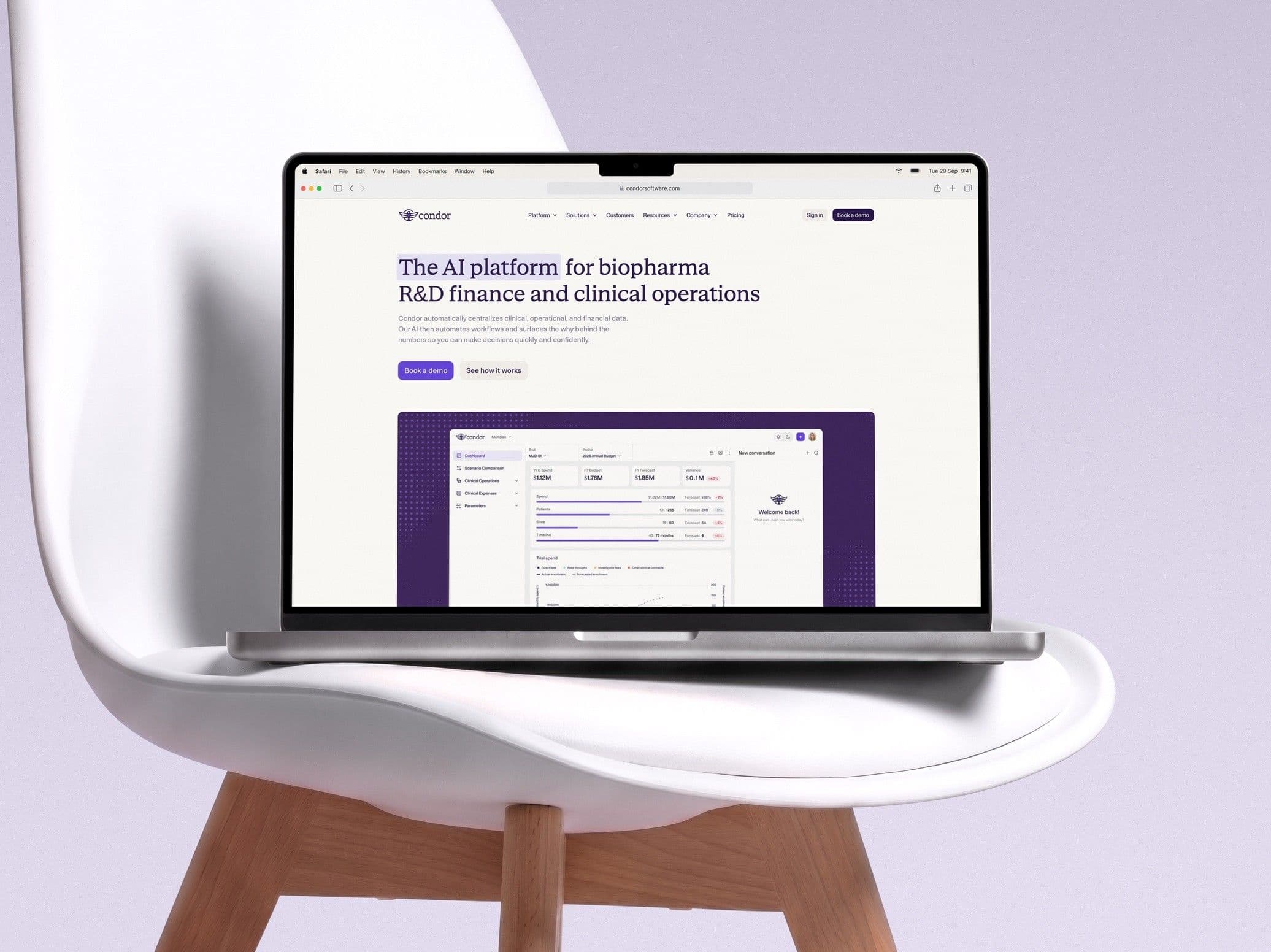 The Condor home page on a MacBook resting on an Eames-style chair, against a lavender wall